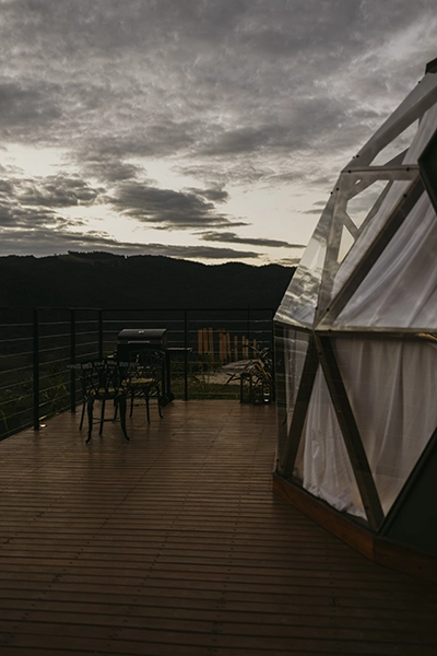 Lateral arquitetônica do domo e deck integrados à beleza natural durante o pôr do sol