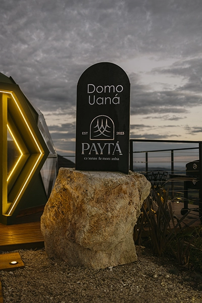 Imponente placa em pedra natural na entrada, marcando a exclusividade do Payta Cabanas