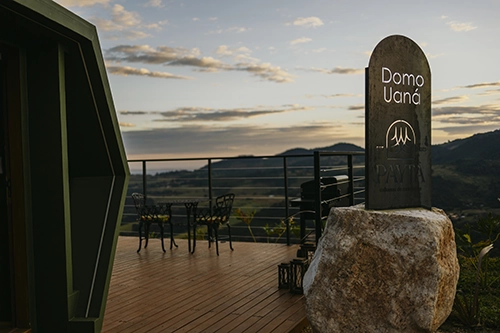 Detalhe arquitetônico do deck com a icônica Pedra Payta na entrada, unindo rusticidade e luxo