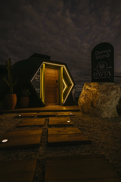 Entrada privativa da cabana iluminada à noite, garantindo exclusividade e romantismo