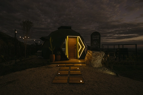 Atmosfera acolhedora: entrada do domo com iluminação cênica noturna impecável