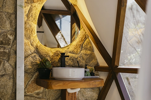 Casa de banho elegante com lavatório rústico, espelho amplo e produtos L'Occitane