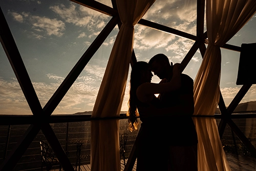 Clima de romance ao entardecer com o casal trocando carinhos no interior aconchegante da cabana