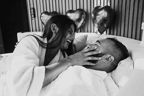 Descontração e alegria: casal rindo e se beijando na cama vestindo os exclusivos e confortáveis roupões Paytá