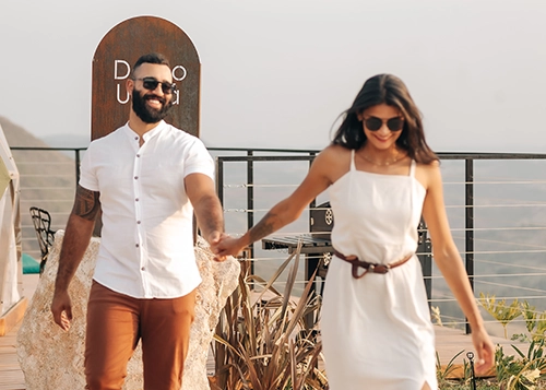 Casal caminhando de mãos dadas pelas instalações da cabana, explorando o conforto e a paz do ambiente